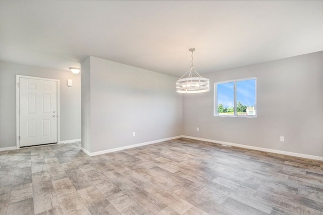 empty room featuring light hardwood / wood-style flooring and an inviting chandelier