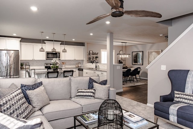 living room featuring dark hardwood / wood-style floors, sink, and ceiling fan with notable chandelier