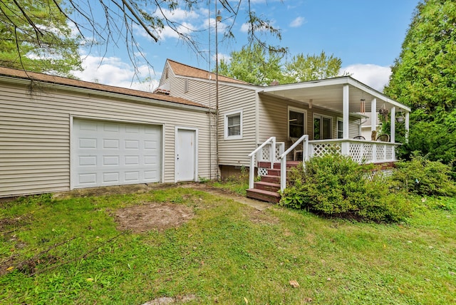 rear view of house with a yard, covered porch, and a garage