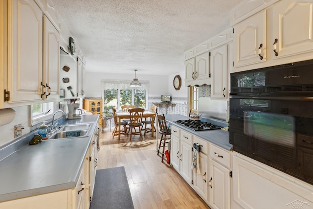 kitchen featuring plenty of natural light, light hardwood / wood-style floors, hanging light fixtures, and black oven