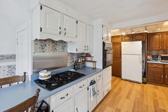 kitchen with tasteful backsplash, white cabinetry, light hardwood / wood-style flooring, and black appliances