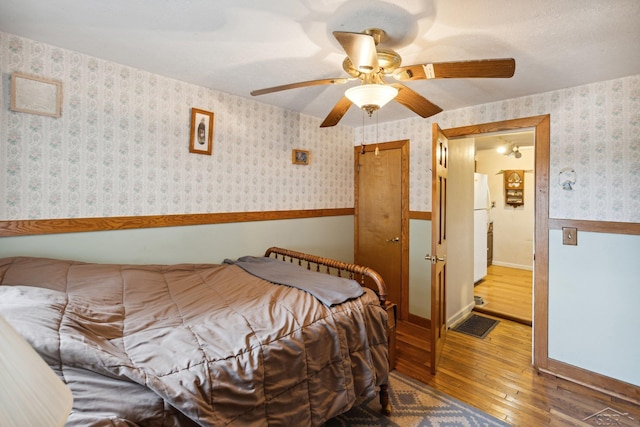 bedroom with white refrigerator, ceiling fan, and dark wood-type flooring