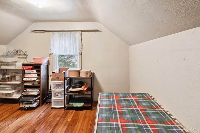 bedroom featuring wood-type flooring, a textured ceiling, and lofted ceiling