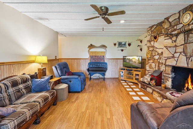 living room with a stone fireplace, ceiling fan, light hardwood / wood-style floors, and a textured ceiling