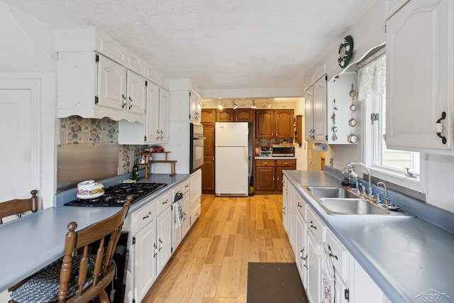 kitchen with white cabinets, appliances with stainless steel finishes, light hardwood / wood-style flooring, and sink