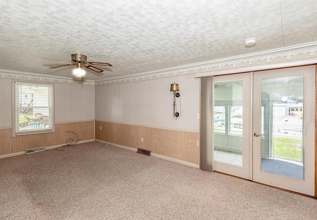 482 Swan Ln, Coldwater, MI 49036 - carpeted empty room featuring a wainscoted wall, a ceiling fan, ornamental molding, wood walls, and french doors
