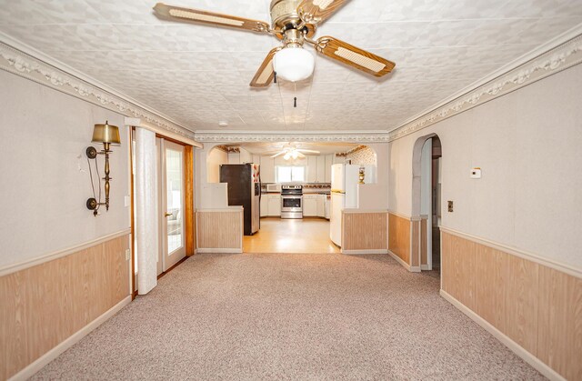 482 Swan Ln, Coldwater, MI 49036 - unfurnished living room with ceiling fan, arched walkways, a wainscoted wall, light colored carpet, and wood walls