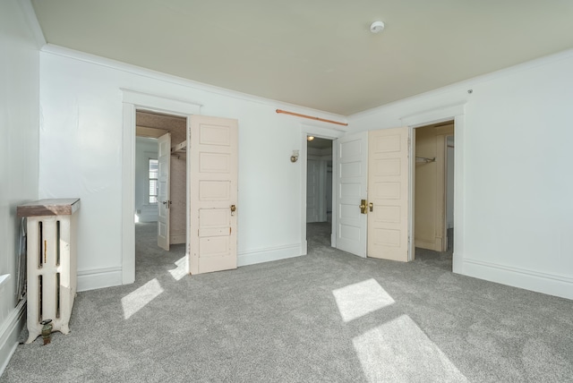 unfurnished bedroom with crown molding, a closet, carpet, and a spacious closet