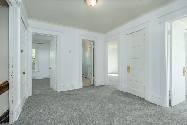 unfurnished bedroom with light carpet, ensuite bath, baseboard heating, crown molding, and a closet