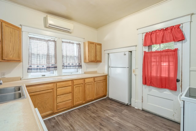 kitchen with stove, an AC wall unit, sink, white fridge, and dark hardwood / wood-style flooring