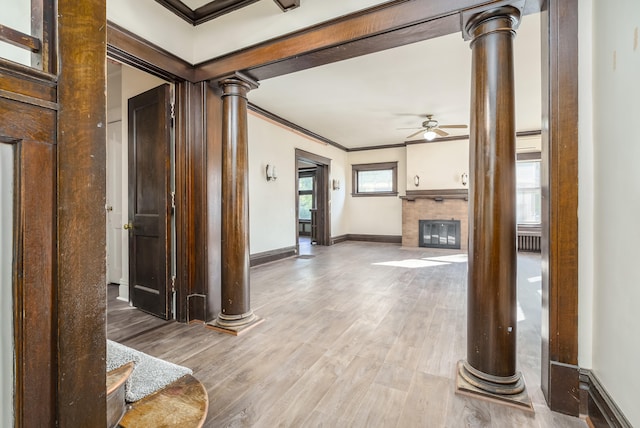 hallway with light wood-type flooring, ornamental molding, and decorative columns