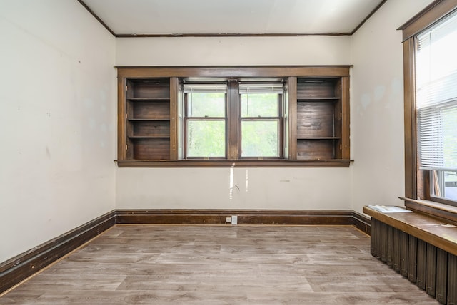 spare room with light wood-type flooring, ornamental molding, and a wealth of natural light