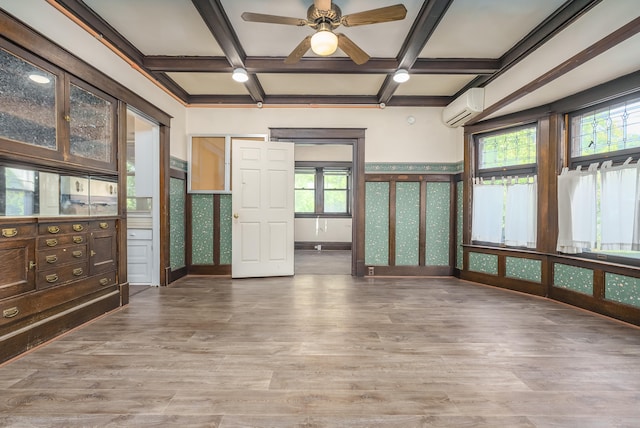 unfurnished room featuring coffered ceiling, an AC wall unit, beamed ceiling, hardwood / wood-style floors, and plenty of natural light