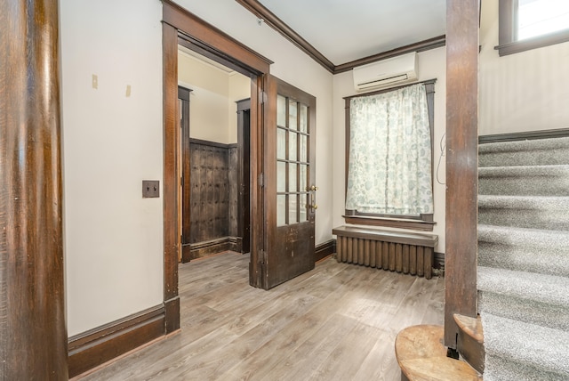 hallway featuring crown molding, radiator heating unit, a wall mounted air conditioner, and light hardwood / wood-style flooring