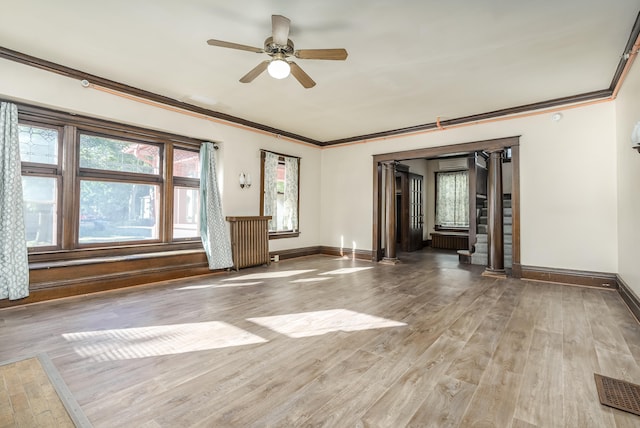 unfurnished room with radiator, crown molding, ceiling fan, light wood-type flooring, and ornate columns