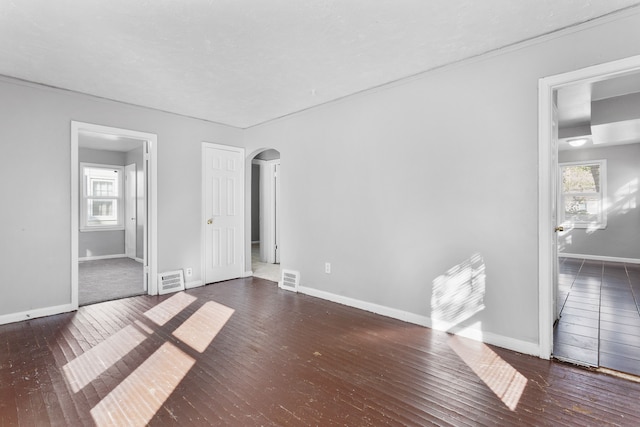 spare room with a wealth of natural light and dark wood-type flooring