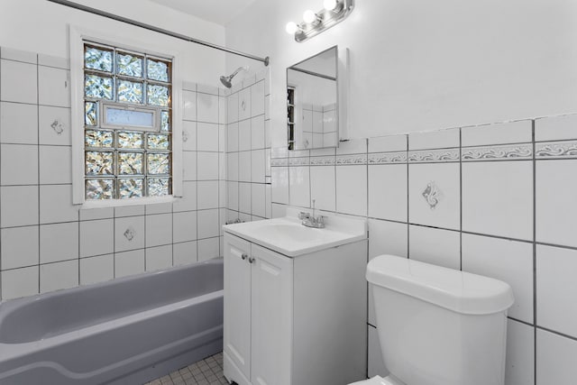 full bathroom with tile patterned flooring, toilet, vanity, tile walls, and tiled shower / bath