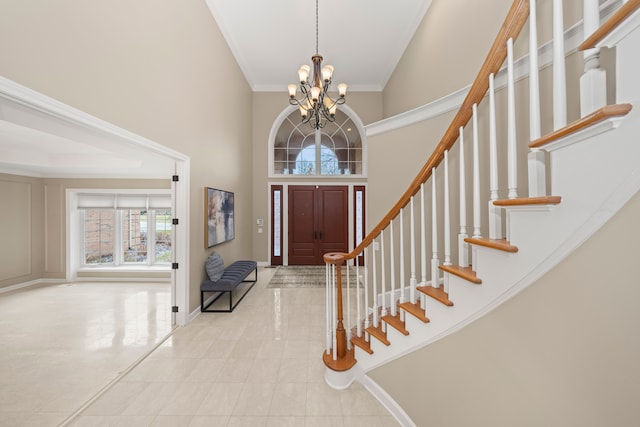 entrance foyer with a towering ceiling, ornamental molding, and a notable chandelier