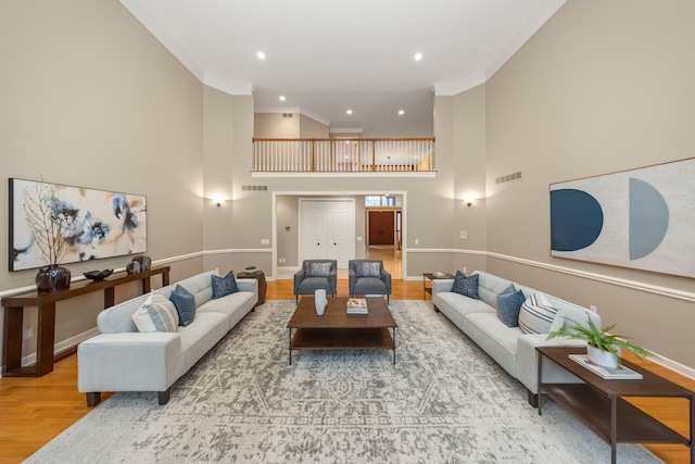 living room featuring a high ceiling, hardwood / wood-style flooring, and crown molding