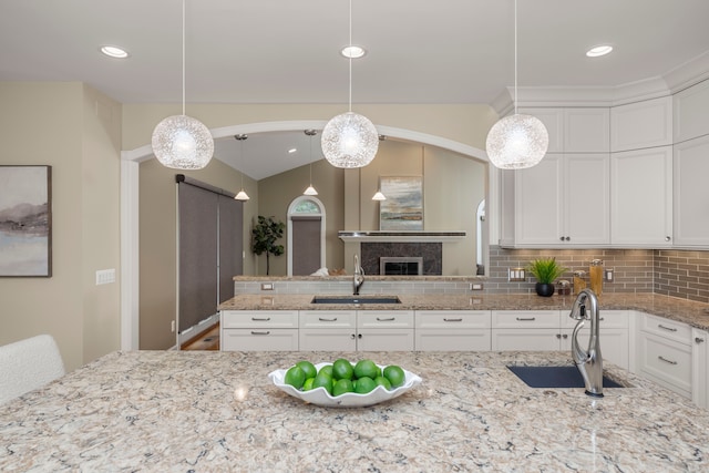 kitchen featuring decorative backsplash, pendant lighting, white cabinets, and sink