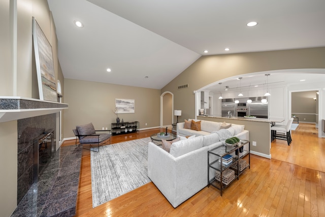 living room with a tile fireplace, hardwood / wood-style floors, and vaulted ceiling