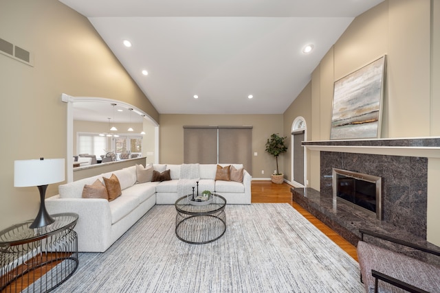 living room featuring a high end fireplace, wood-type flooring, and lofted ceiling