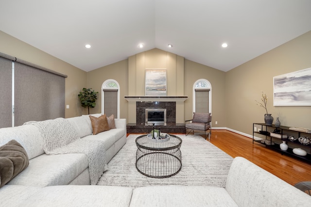 living room featuring hardwood / wood-style floors, lofted ceiling, and a premium fireplace