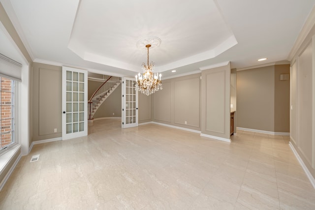 unfurnished room featuring french doors, a tray ceiling, an inviting chandelier, and crown molding