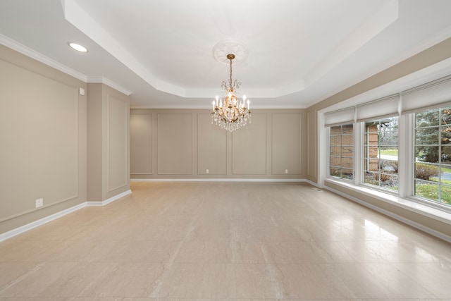 unfurnished room featuring a tray ceiling, ornamental molding, and an inviting chandelier