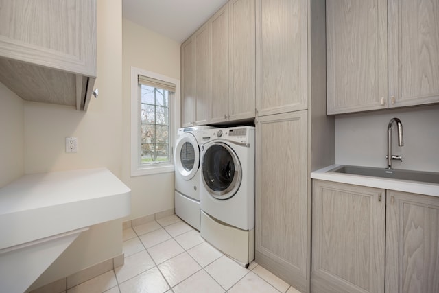 laundry room featuring sink, light tile patterned floors, cabinets, and independent washer and dryer