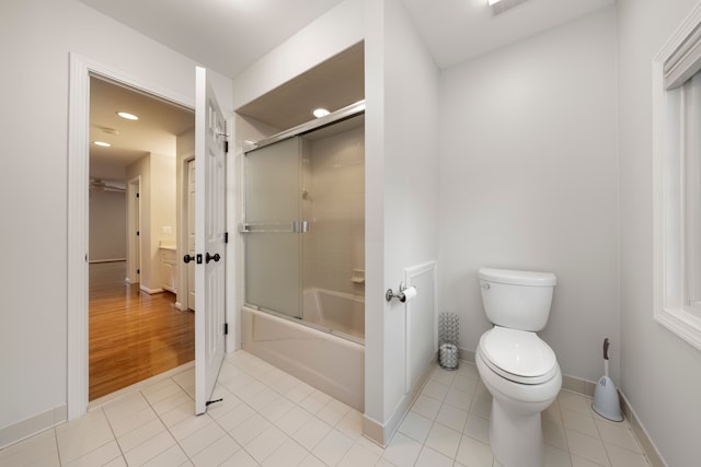 bathroom featuring tile patterned flooring, toilet, and bath / shower combo with glass door