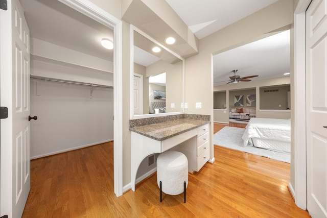 interior space with white cabinets, ceiling fan, light hardwood / wood-style floors, and dark stone counters