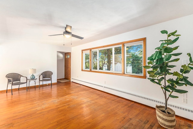 sitting room with hardwood / wood-style flooring, ceiling fan, and a baseboard heating unit