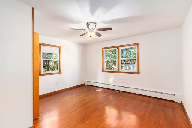 empty room featuring baseboard heating, ceiling fan, and wood-type flooring