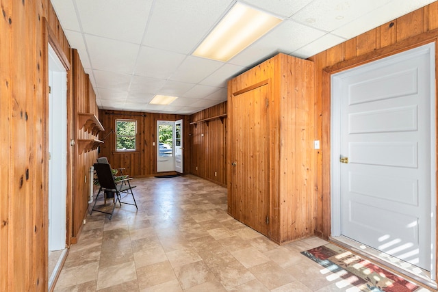 foyer entrance featuring a paneled ceiling and wood walls