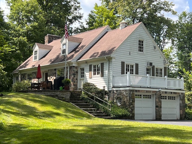 cape cod home with a garage and a front lawn