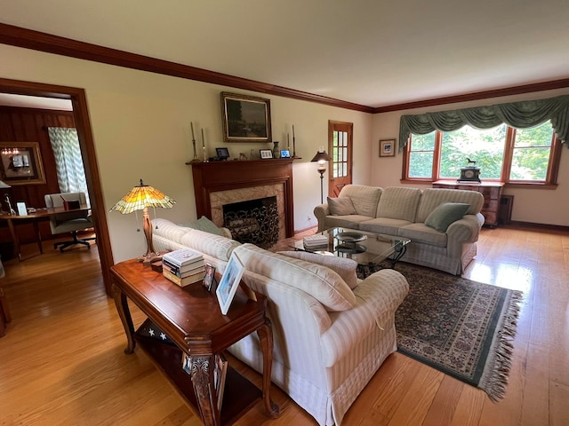 living room featuring a premium fireplace, ornamental molding, and light wood-type flooring