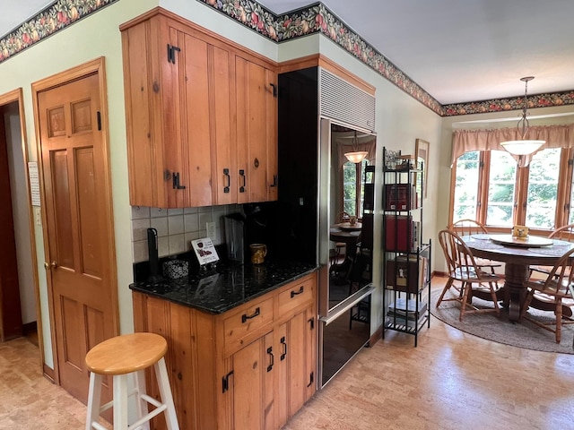 kitchen featuring light wood-type flooring, pendant lighting, backsplash, and dark stone counters