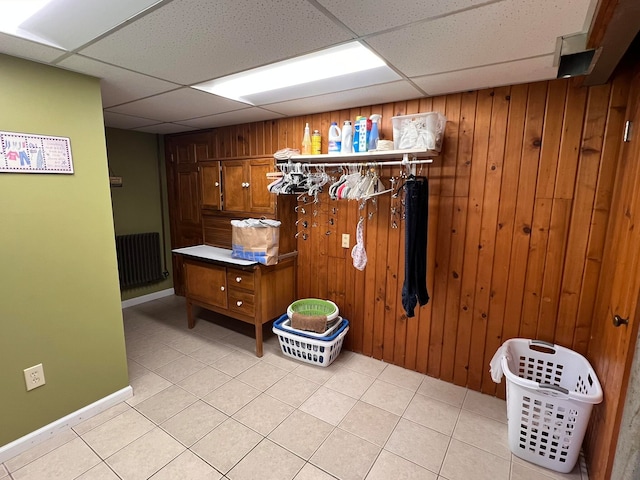 laundry room featuring wood walls, light tile patterned flooring, and radiator heating unit