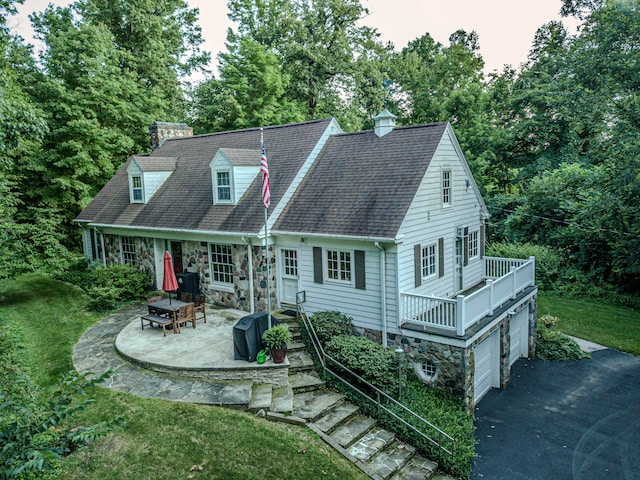 cape cod home featuring a yard, a balcony, a garage, and a patio area