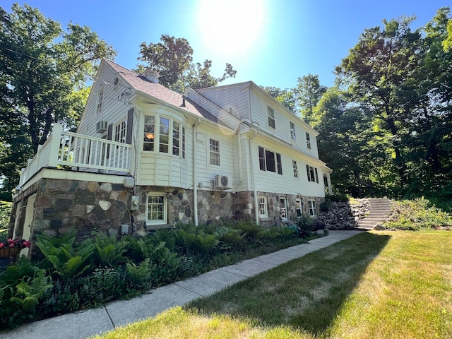 view of property exterior with a lawn, a balcony, and ac unit