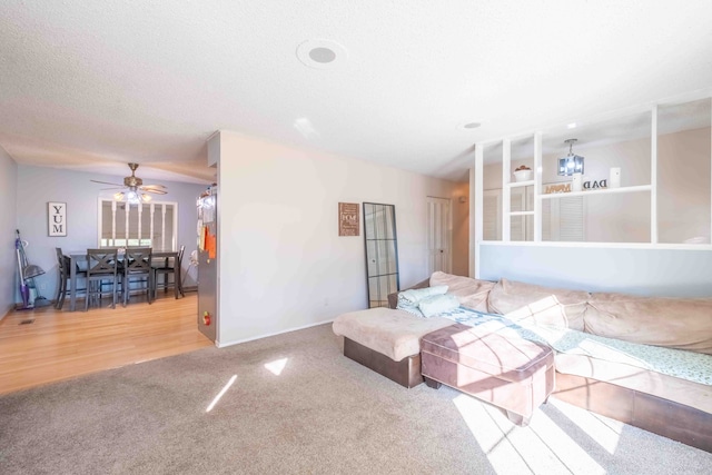 living room with a textured ceiling, light hardwood / wood-style flooring, and ceiling fan