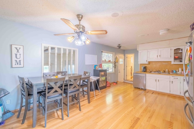 dining space with ceiling fan, light wood-type flooring, and a textured ceiling