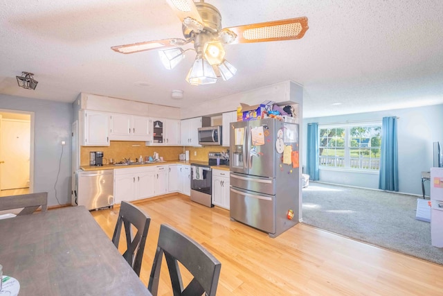 kitchen with light hardwood / wood-style flooring, ceiling fan, a textured ceiling, appliances with stainless steel finishes, and white cabinetry