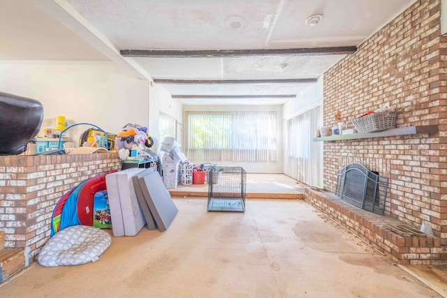 rec room with beam ceiling, a textured ceiling, and a brick fireplace