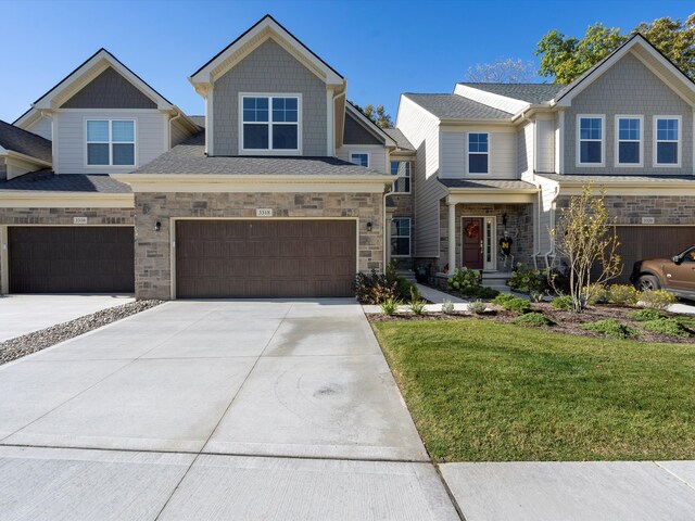 3318 Roseford Blvd, Ann Arbor, MI 48105 - craftsman-style house featuring an attached garage, driveway, a front lawn, and stone siding