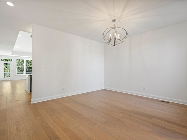 unfurnished room with an inviting chandelier and light hardwood / wood-style flooring