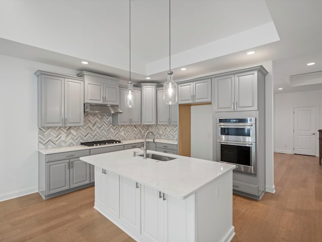 kitchen featuring stainless steel appliances, a center island with sink, light hardwood / wood-style floors, and sink