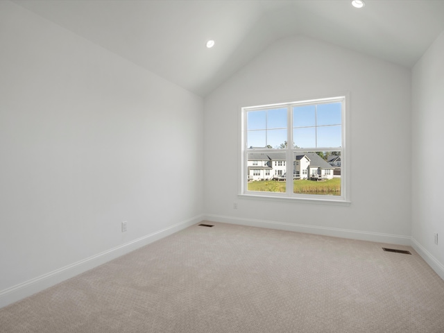 carpeted empty room with vaulted ceiling