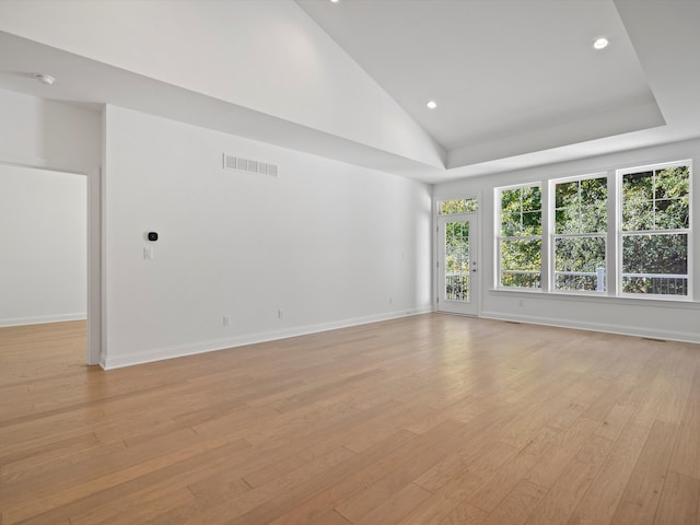 spare room featuring high vaulted ceiling and light hardwood / wood-style flooring